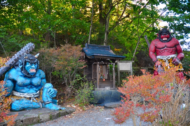 Noboribetsu Onsen - Noboribetsu Onsen Travel Guide | Best Hot Springs in Hokkaido Colorful oni statues guarding a small shrine at Noboribetsu Onsen, surrounded by vibrant autumn foliage.