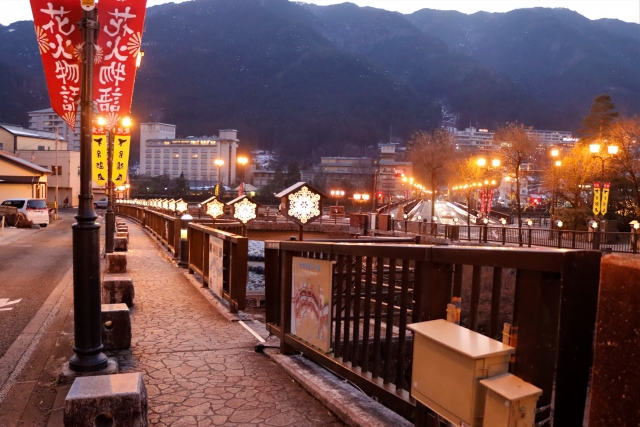 Gero Onsen - Gero Onsen: Discover One of Japan’s Top 3 Hot Springs Rainy evening in Kinosaki Onsen with willow-lined canal, traditional ryokan, and visitors crossing the bridge with colorful umbrellas.