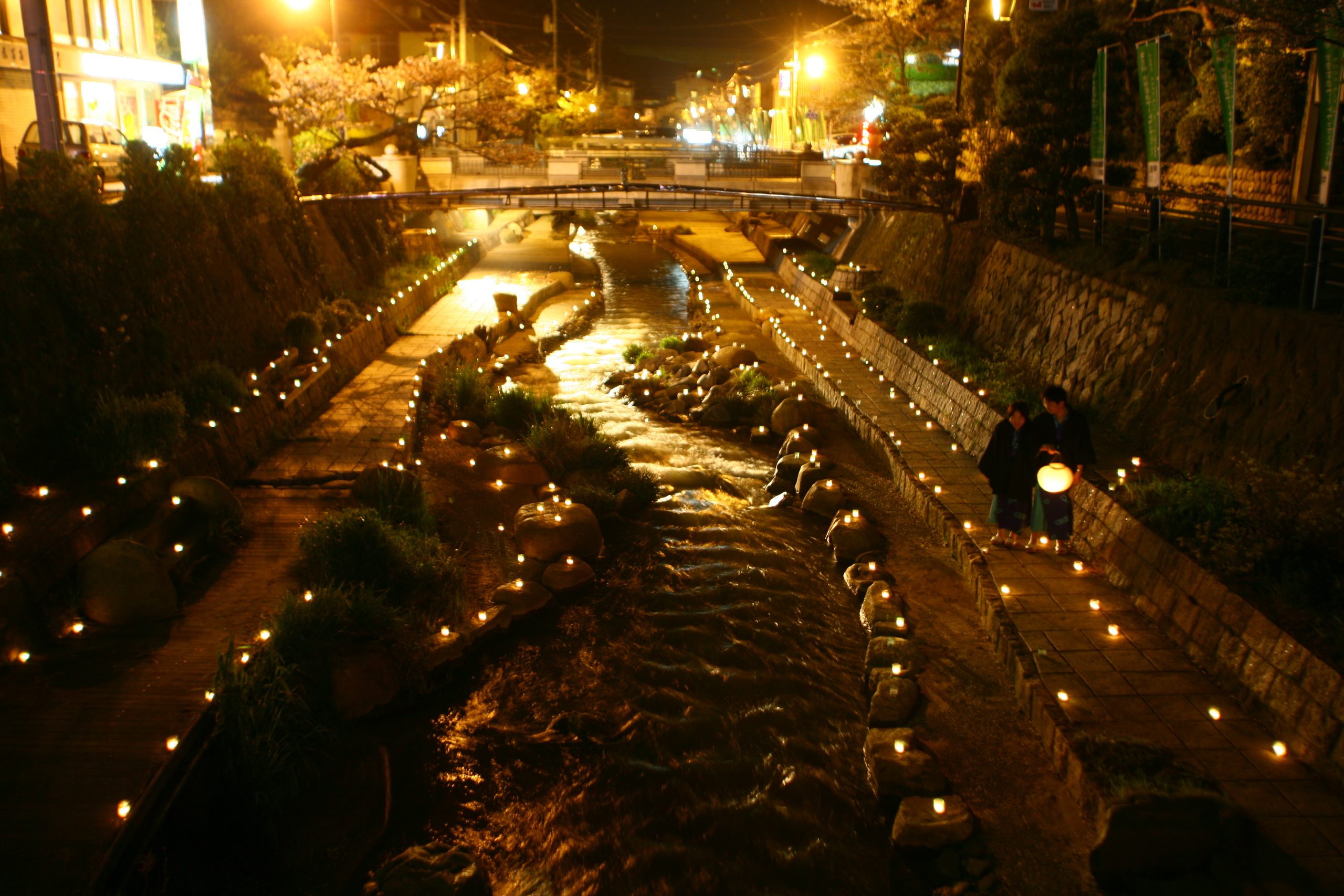 Tamatsukuri Onsen Izumo illuminated riverside path with glowing lanterns creating a magical night scene.