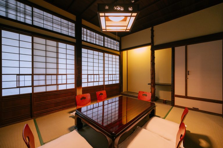 Traditional Japanese tatami room at Dogo Onsen, featuring shoji screens, a low wooden table, and zabuton seating for a serene and authentic experience.