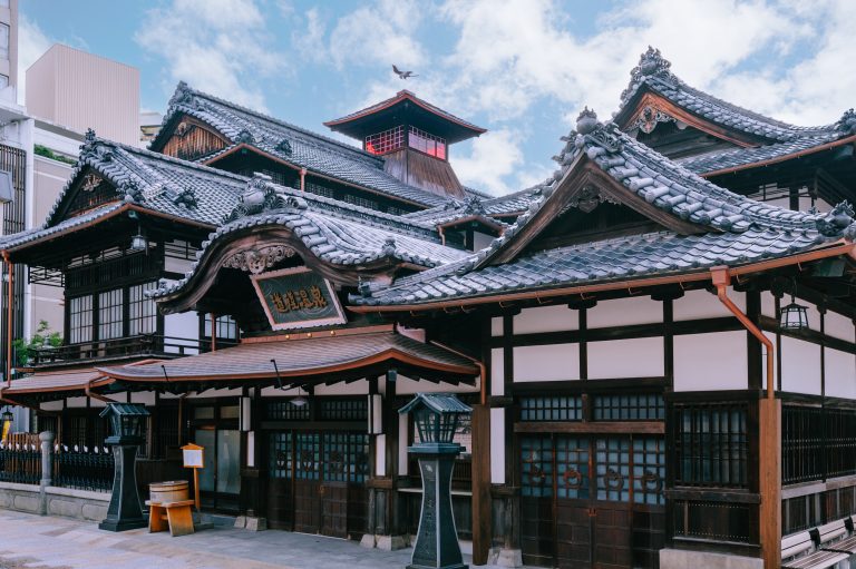 The iconic Dogo Onsen Honkan, a historic wooden bathhouse with traditional tiled roofs, symbolizing Japan’s oldest hot spring.