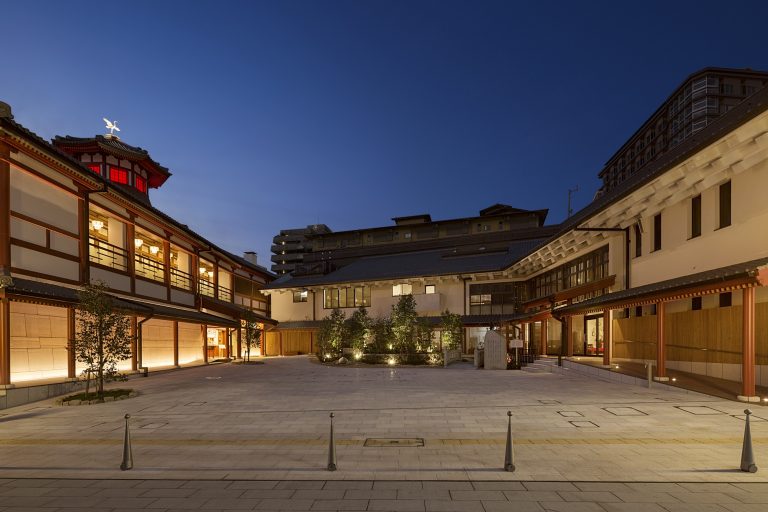 Evening view of the Dogo Onsen Annex Asuka-no-Yu, with traditional Japanese architecture illuminated against the twilight sky.